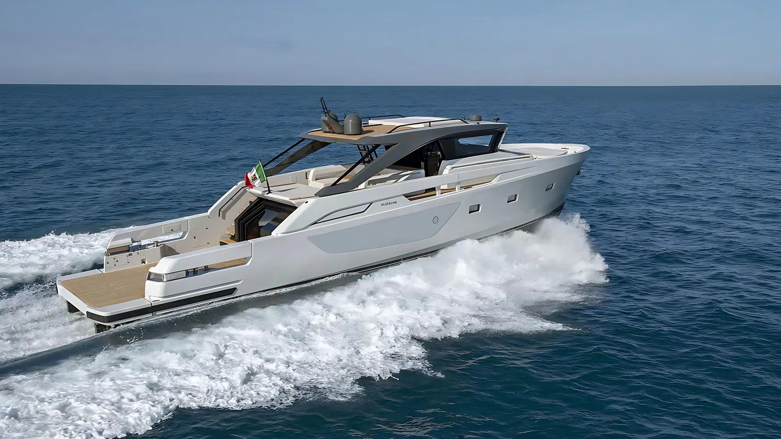 Bluegame 74 running at speed across open blue sea, a wide white wake trailing her teak bathing platform