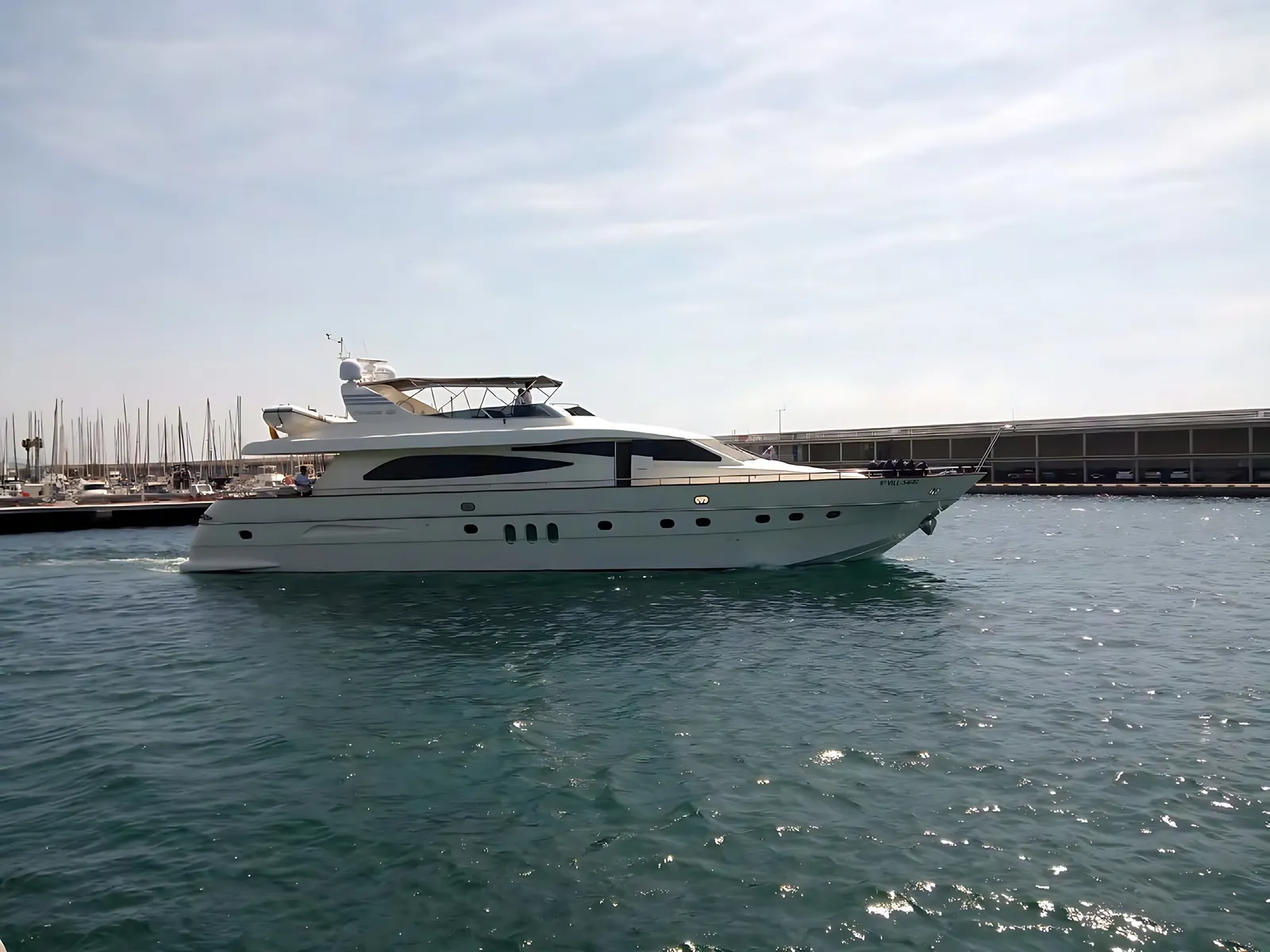 Canados 86 motor yacht under way through calm harbour water, with the flybridge bimini raised