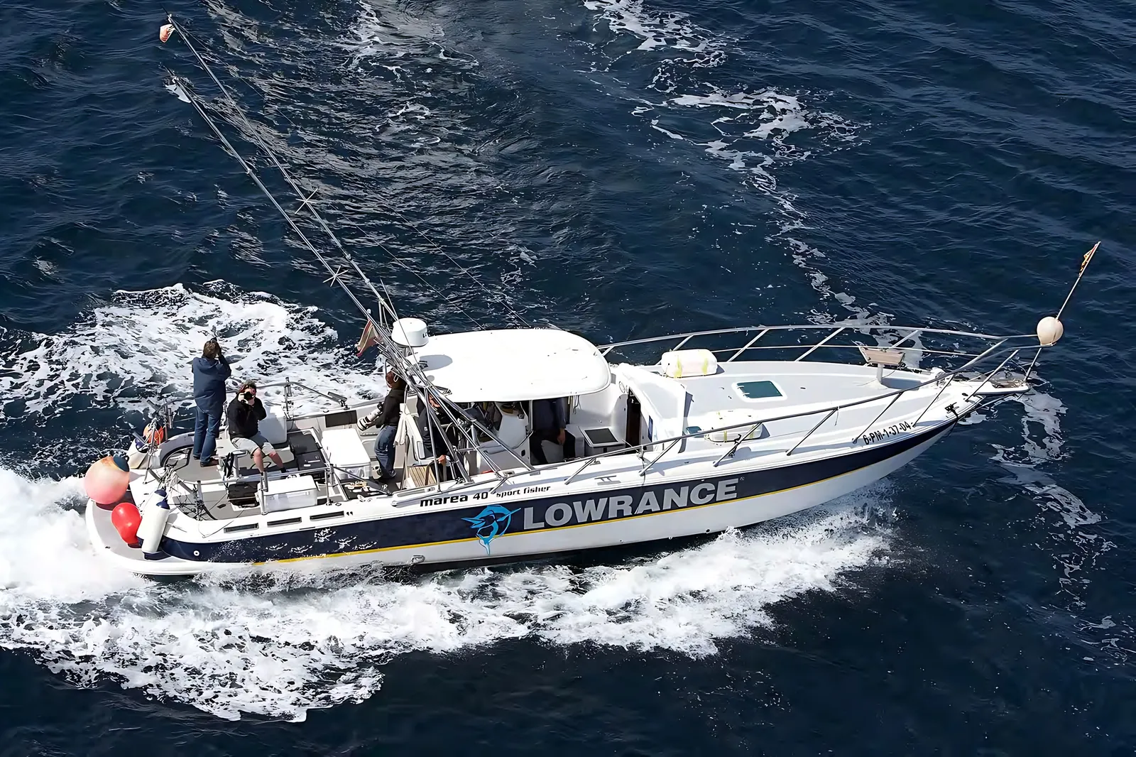 Aerial view of the Fishing Boat at speed on dark blue sea, with outriggers, a hardtop and people in the cockpit