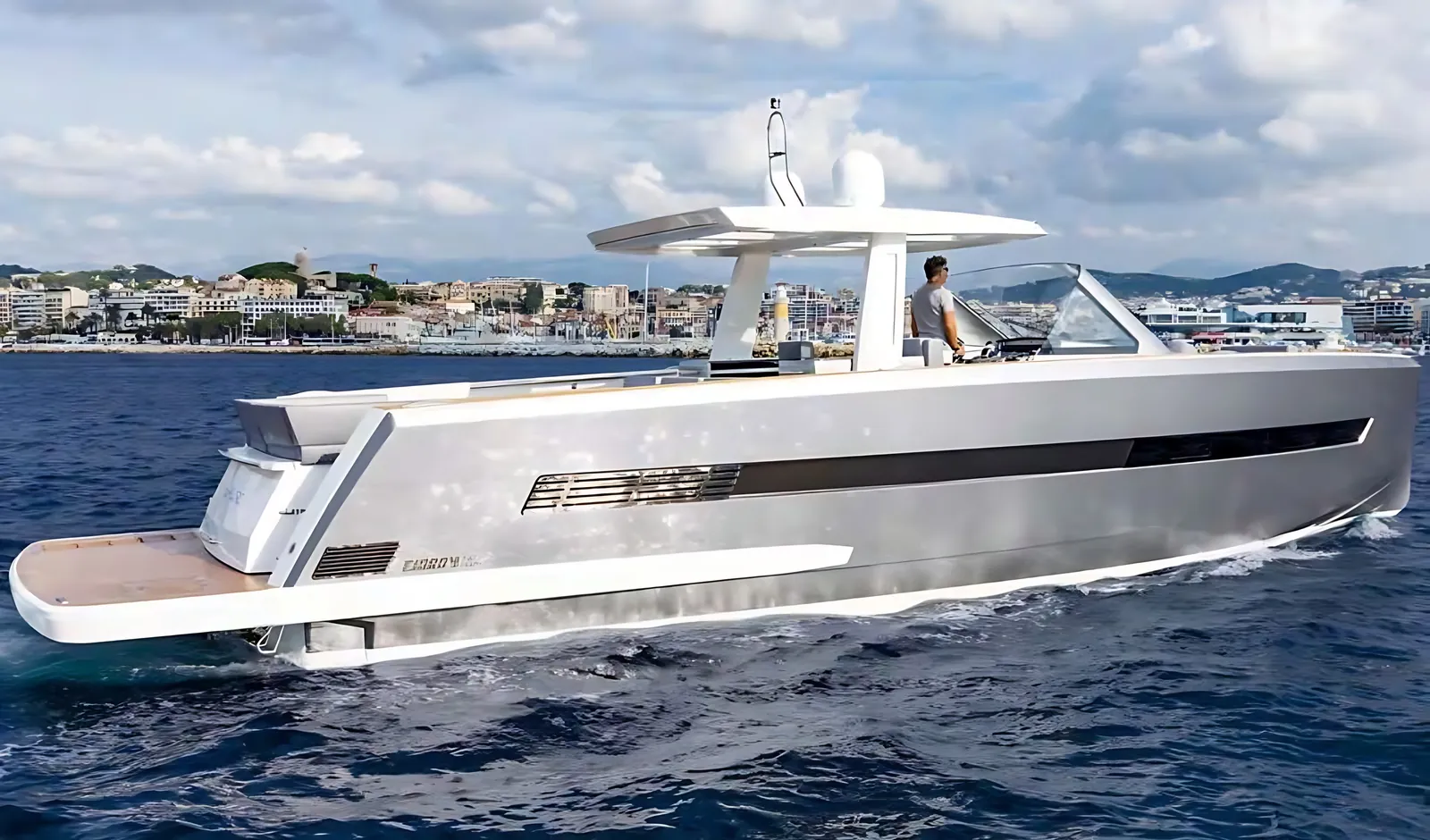 Fjord 52 running at speed, side view of her silver hull, dark side glazing, T-top and wide teak stern platform