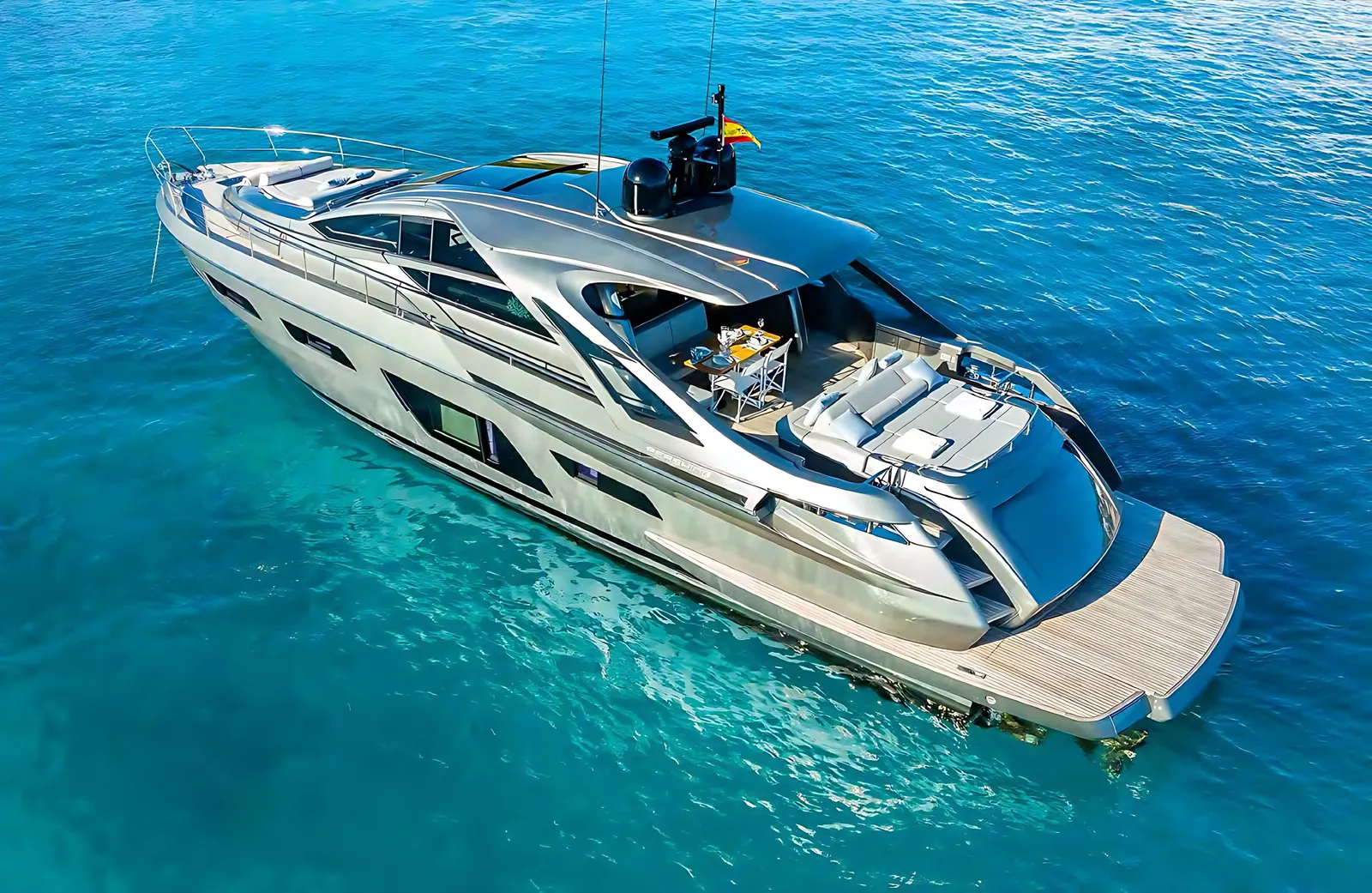 Pershing 7X at anchor in turquoise water, aerial view of her silver hull, cockpit and teak bathing platform