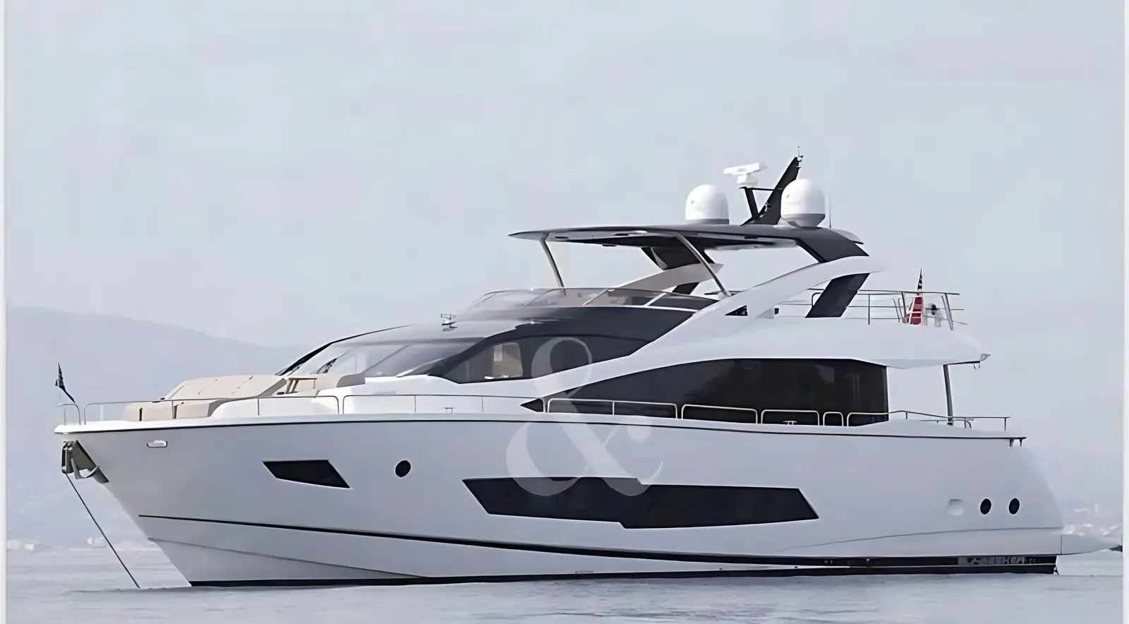 Sunseeker 86 at anchor on calm water, side view of her hardtop flybridge and dark hull windows