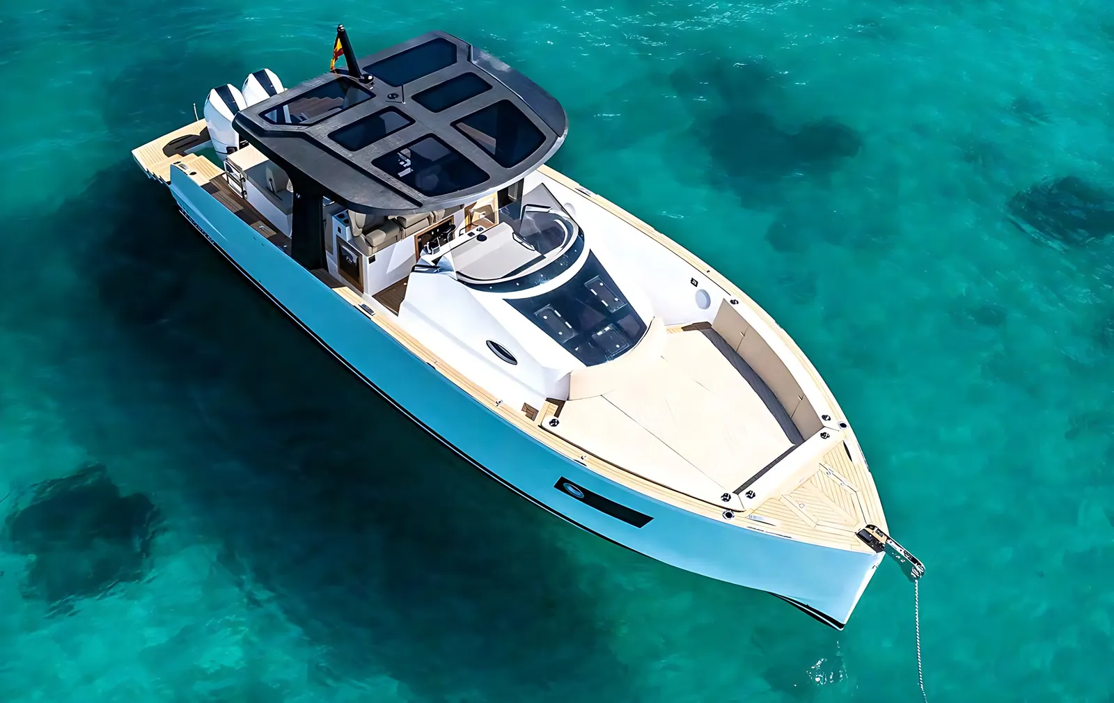 Tesoro 40 at anchor over sand and seagrass in turquoise water, seen from above with her carbon T-top